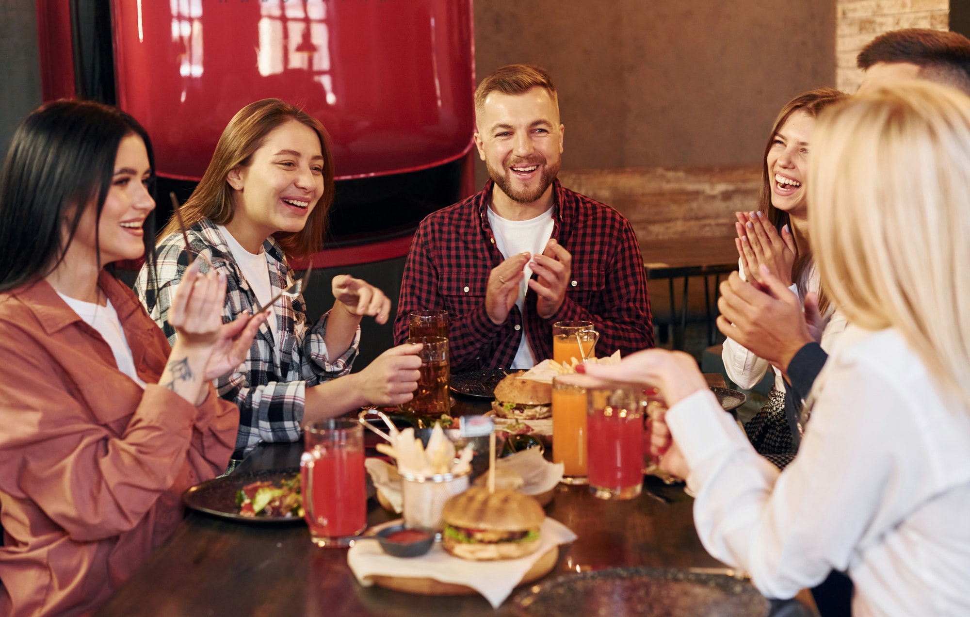 Having a conversation with each other. Group of young friends sitting together in bar with beer